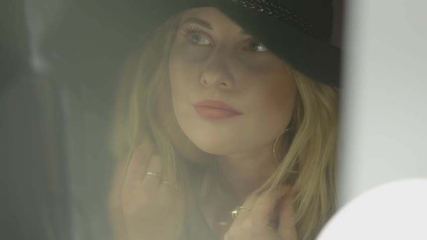 Blonde woman in hat playing with hair
