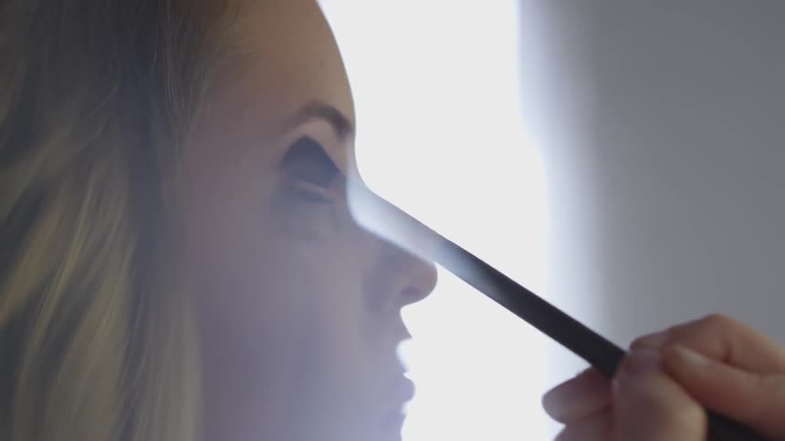 A woman is putting makeup on indoors