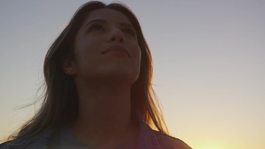 Middle age woman facing you smiles and looks up to the sky