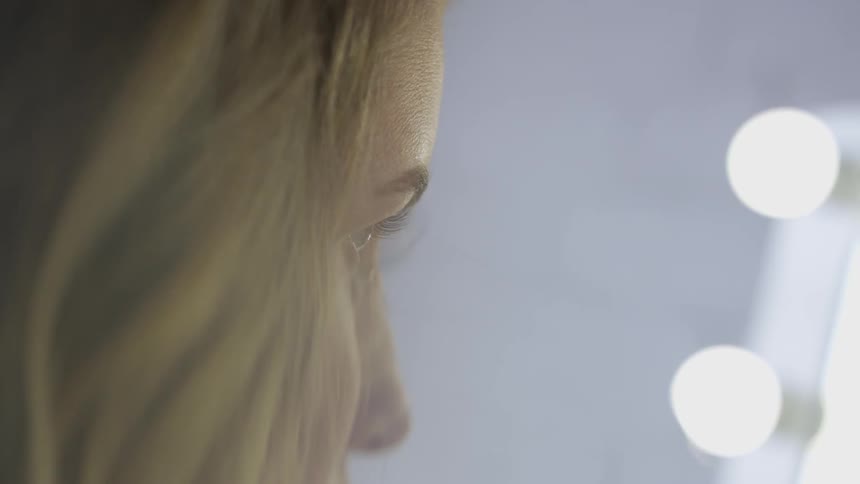 A woman is applying makeup to herself indoors
