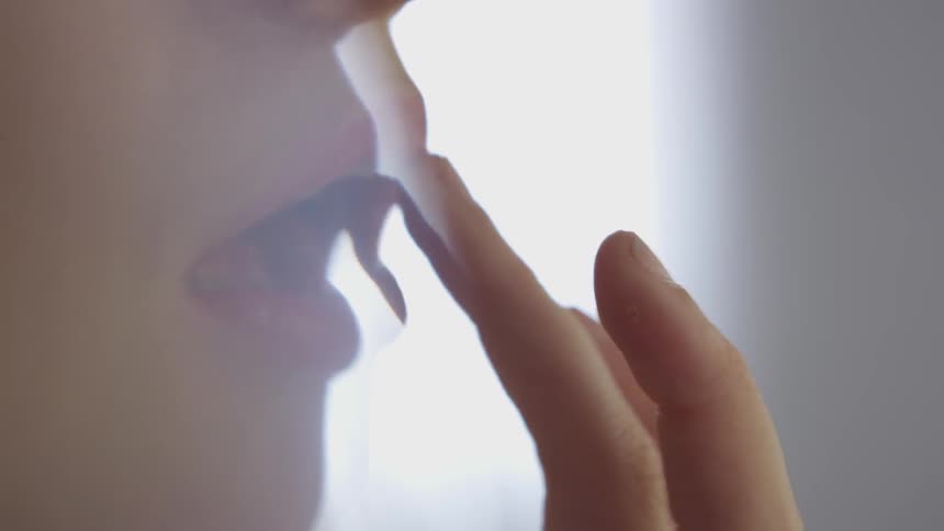 Woman retouching lipstick with fingertips