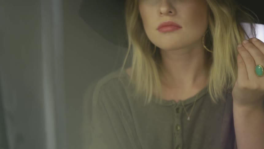 Woman wearing hat touches the ends of her hair