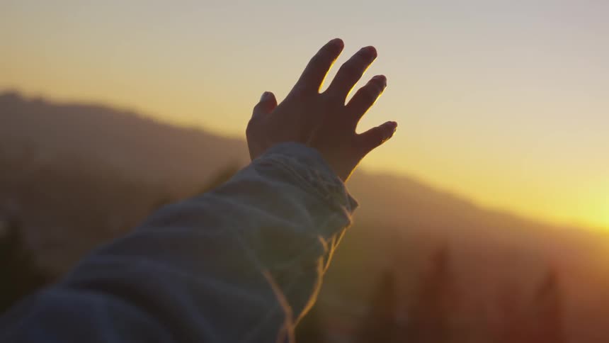Woman stretches hand towards the sun