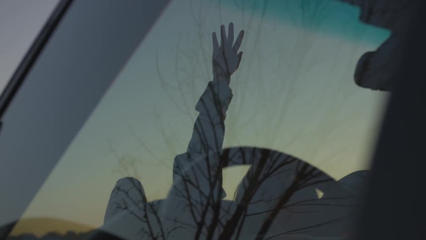 A person is lying on their car outside