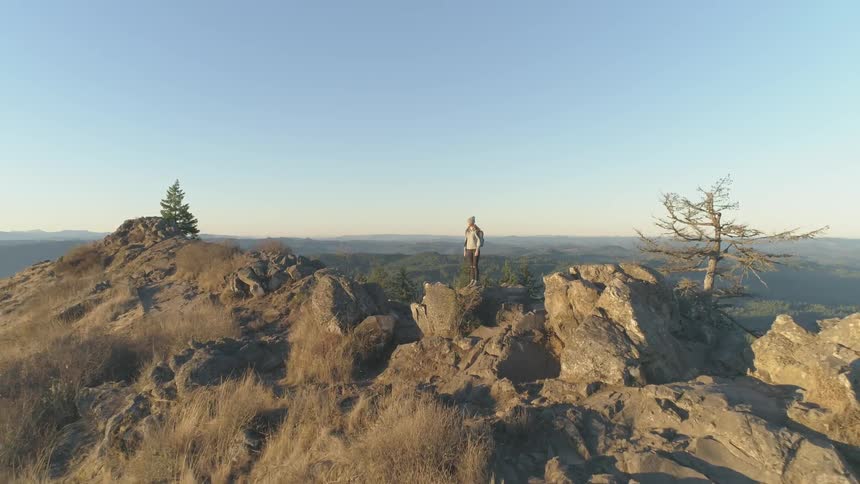 A woman is standing on a cliff outdoors