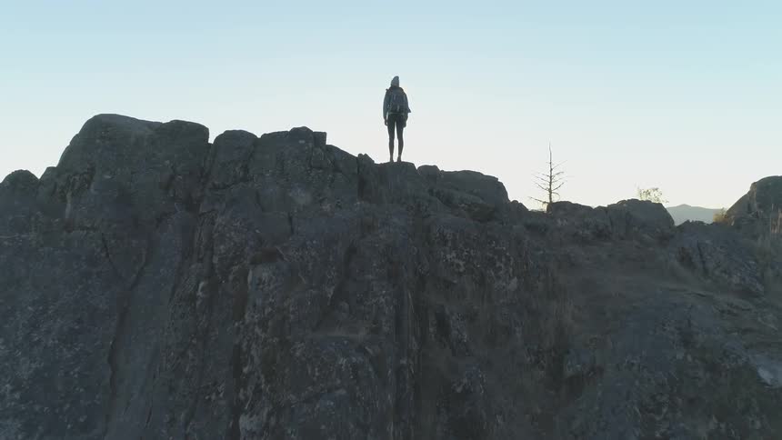 A woman is standing on top of a cliff