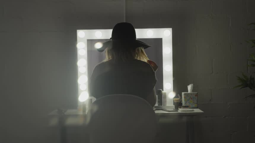 A woman playing with her hair in front of a vanity