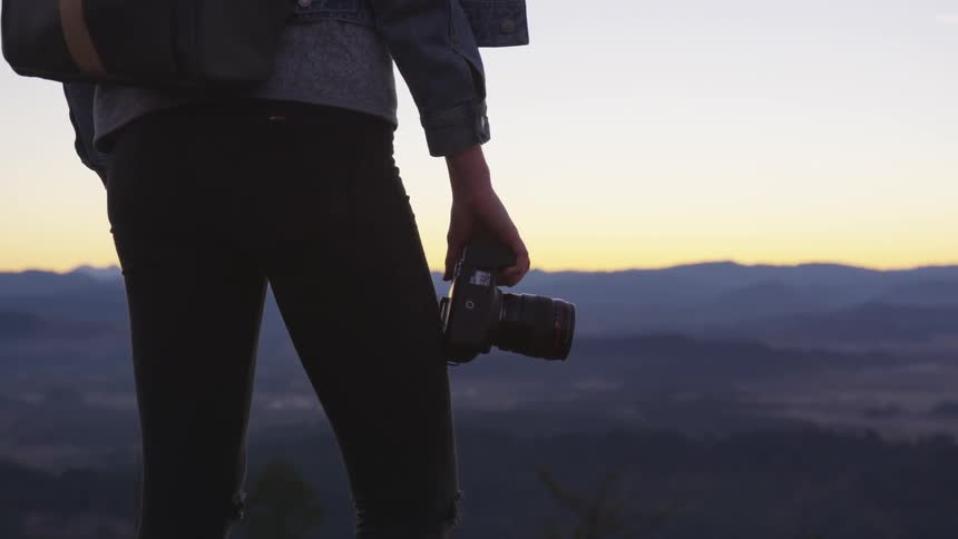 A man standing at the edge of a cliff holding a camera