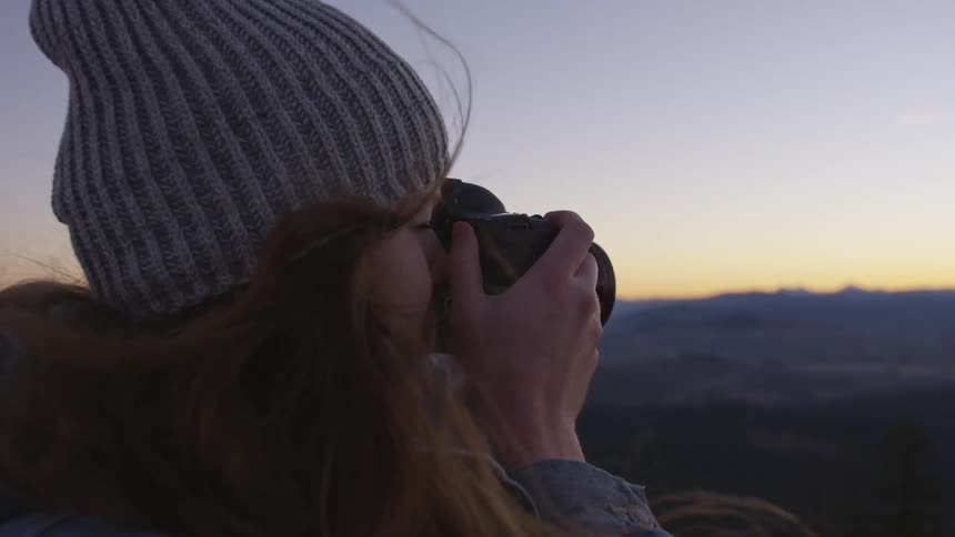 A woman is using a video camera outdoors
