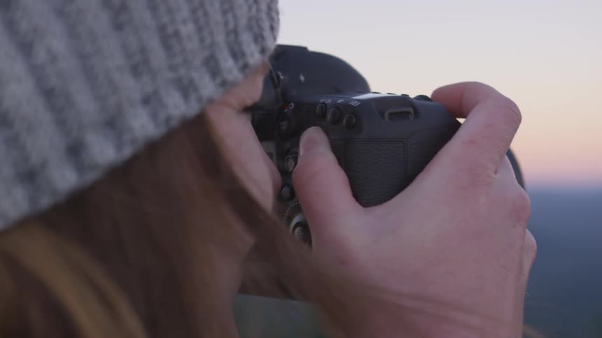 Woman taking photographs outdoors at sunset