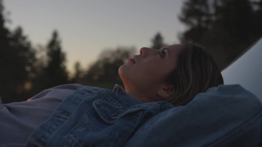 A white woman lies on her back and stares into the sky