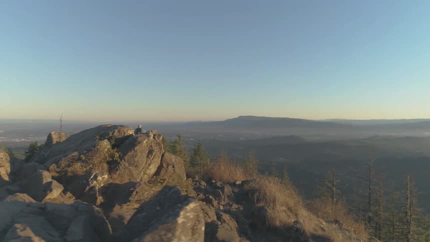 A young white woman walks across the top of a rocky mountain