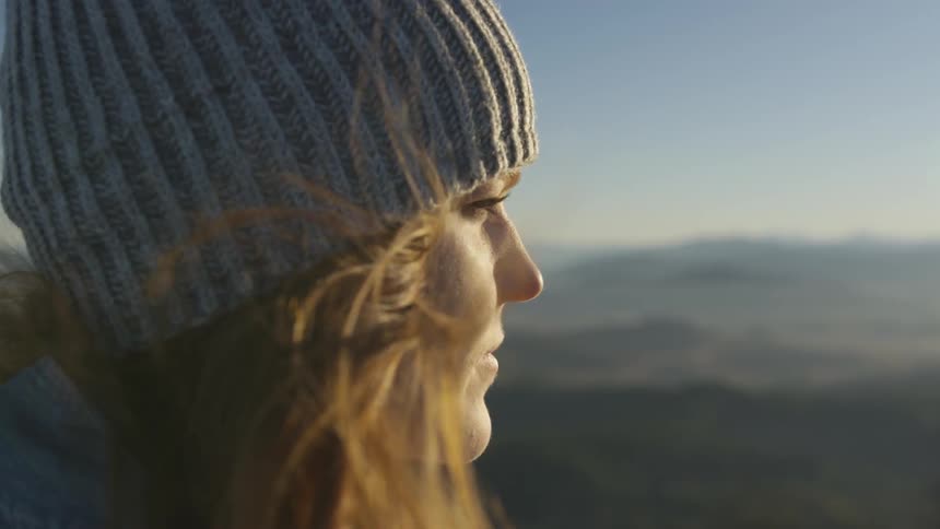 A woman wearing a knit cap stares into the distance