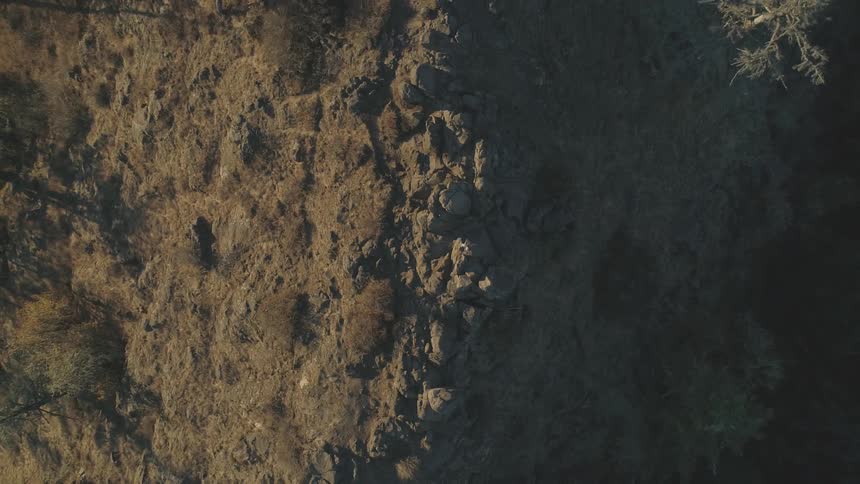Aerial view of a man hiking over the sharp ridges of a hill