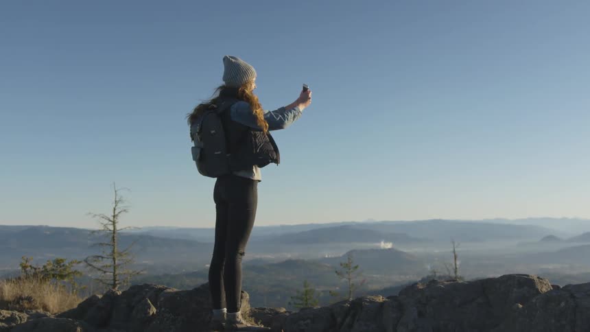A woman is taking a picture with her phone outdoors