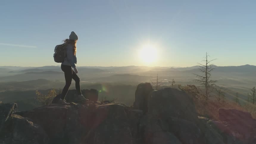 A woman hikes in the mountains at sunrise