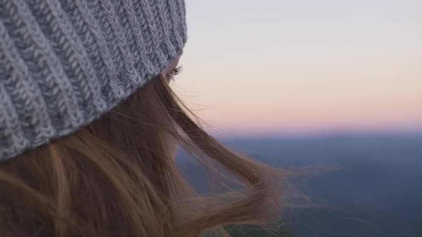 A woman in a beanie looks over scenery