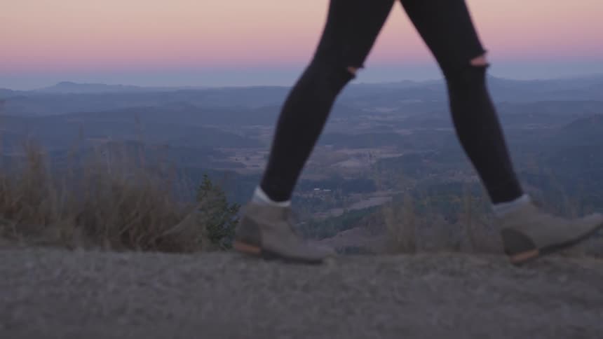 Woman wearing ripped jeans walks in mountain at dusk