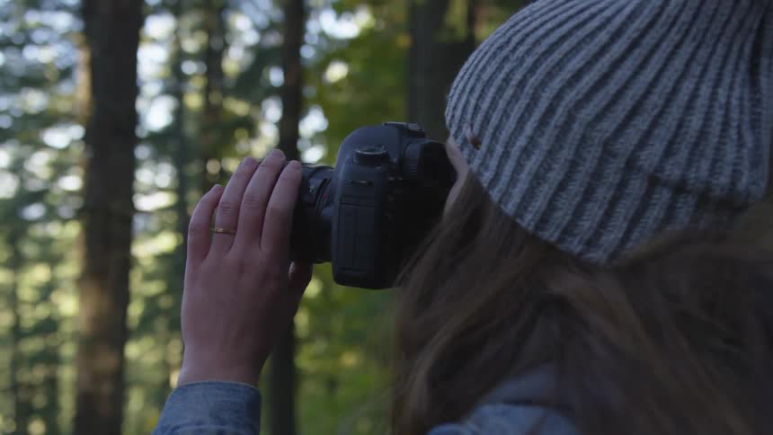 Woman takes a photograph in the forest