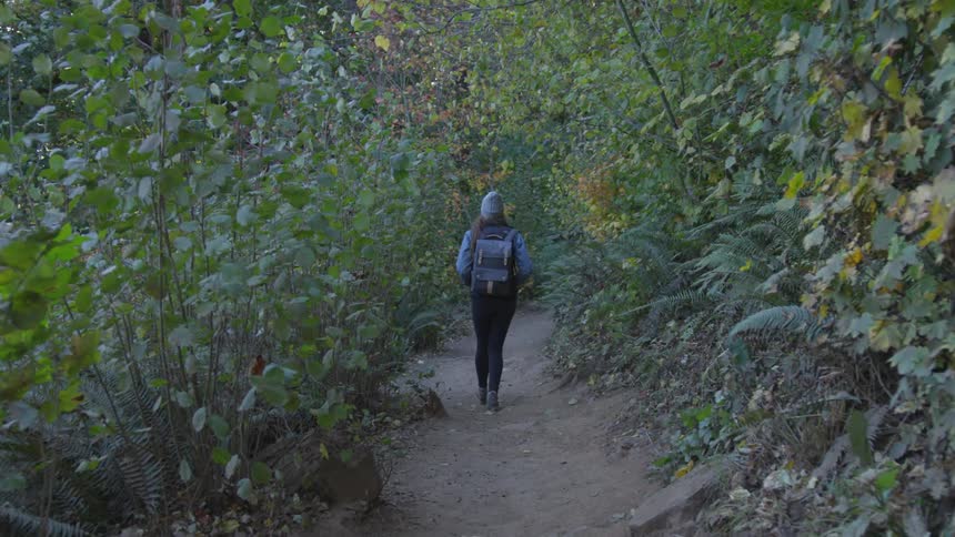A woman hiking down a trail in a forest