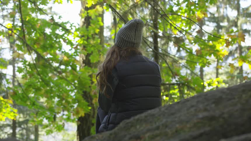 A woman sitting on a rock in a woodland