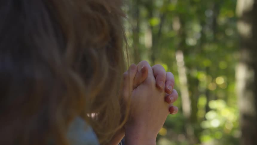 A woman sits with her hands clasped together