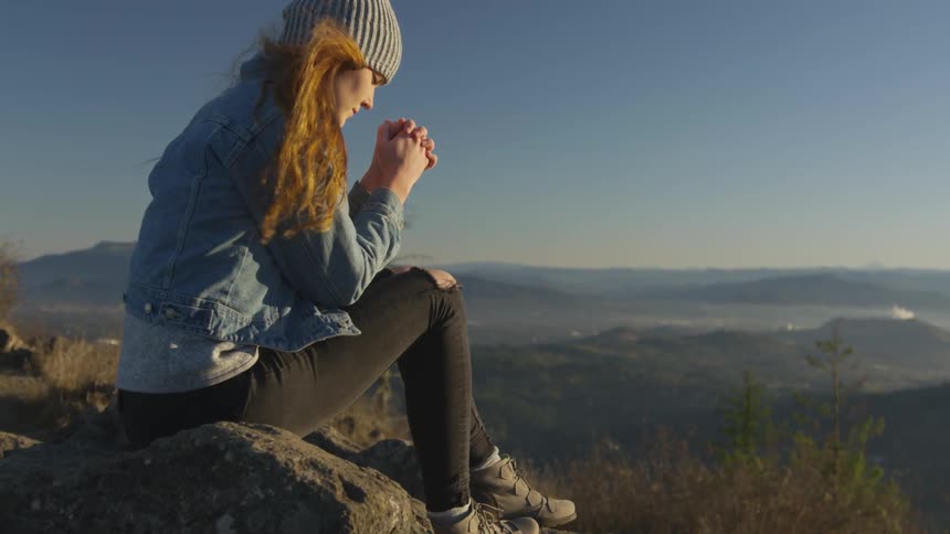 Woman sitting on a rock praying