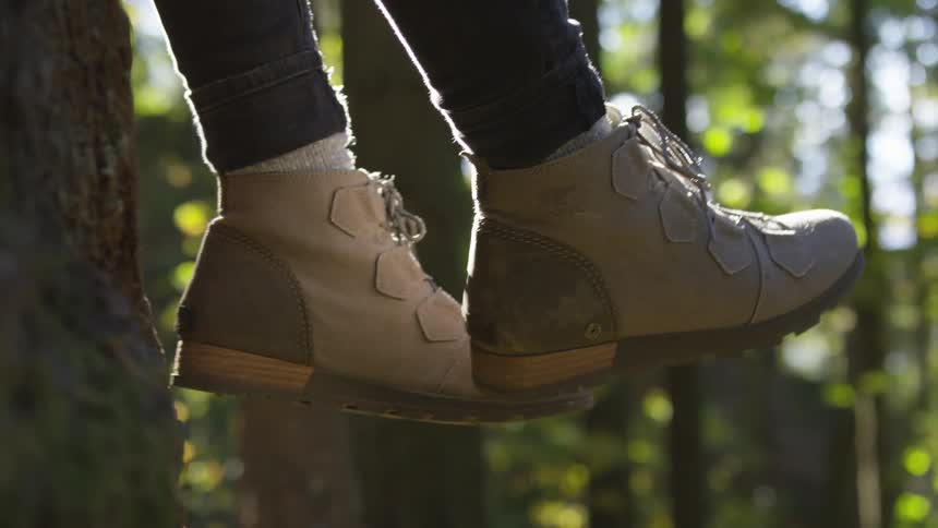 Feet in hiking boots swinging back and forth in forest