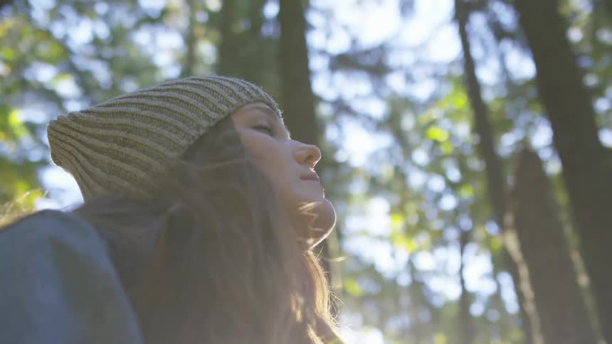 Woman in the woods standing with her eyes closed
