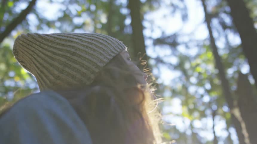 Woman looking up to the trees while sitting in the middle of a forest