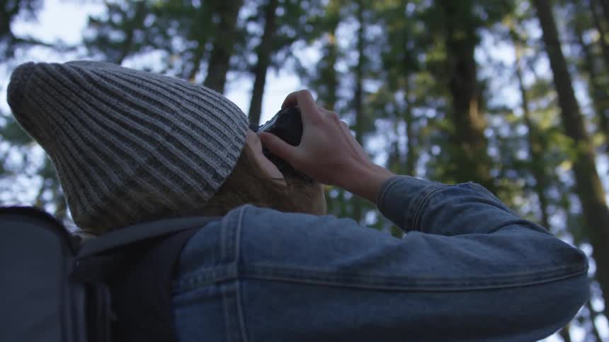 Person hiking in the woods takes picture of sky with camera