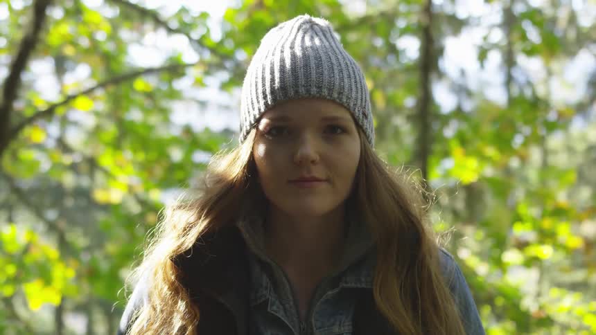 A woman in a beanie standing in the forest