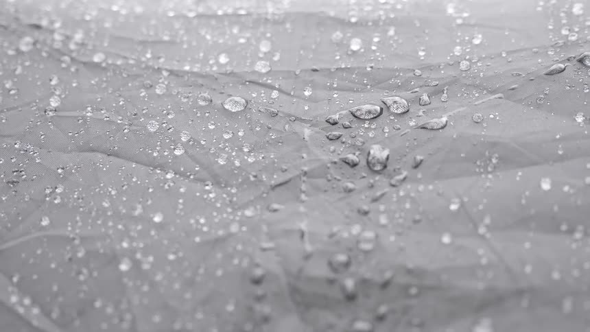 Rain drops fall and cling to a leaf