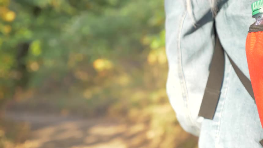 Person with backpack walks along trail in woods