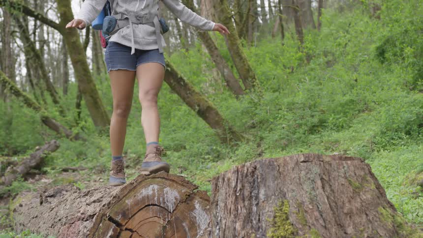 A woman walking a balance beam on a log