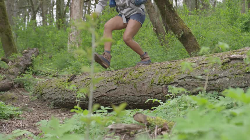 Black woman hiking in the woods and jumping through a tree trunk