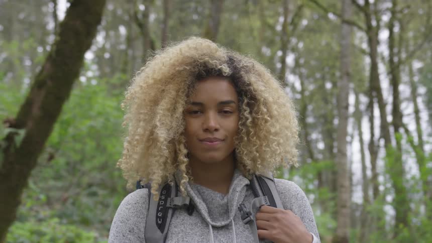 A black woman stands in a forest