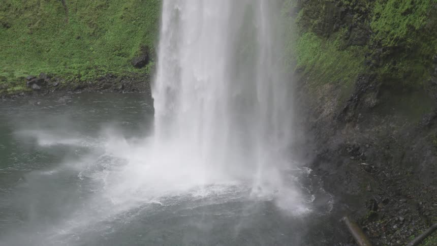 Waterfall flows down the cliff and makes foam in the daytime