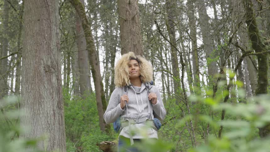 Woman stands smiling in wilderness