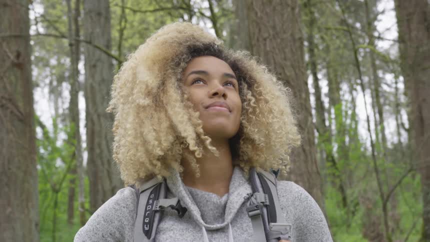 Woman looks around as she stands in the forest