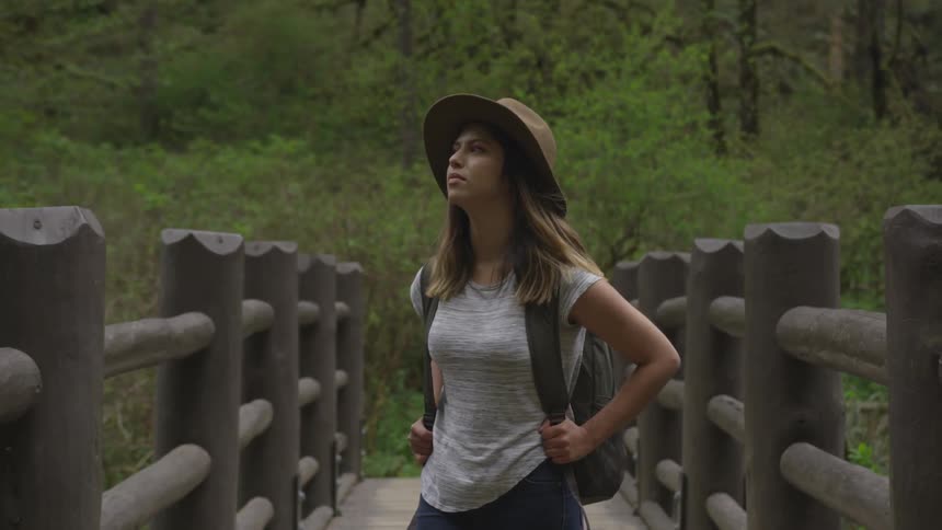 Woman crossing a narrow wooden bridge on a forest