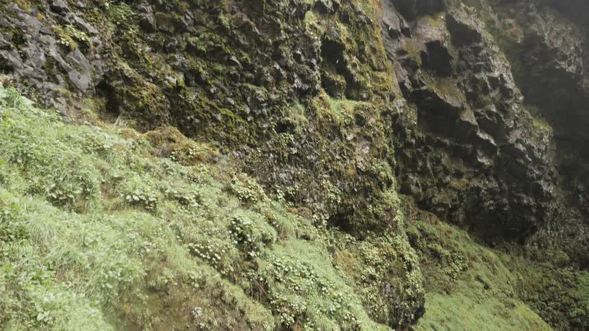 Camera watches water drops fall down a cliff side