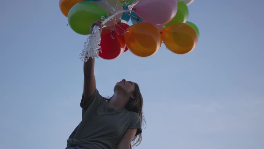 Person holds a large bunch of balloons