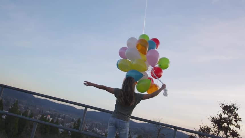 It's somebody holding balloons looking up at the sky with their arms out sky is blue does a chemtrail