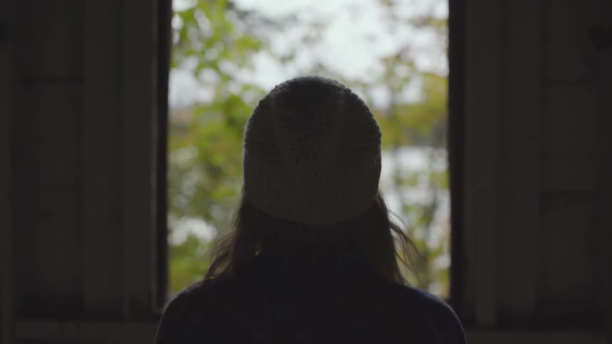Woman looking to a tree through a window