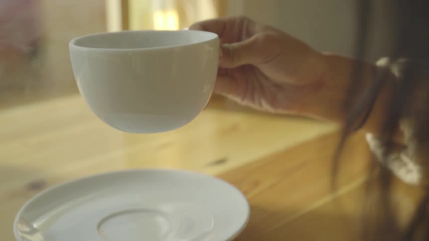 A woman picks up a cup of coffee