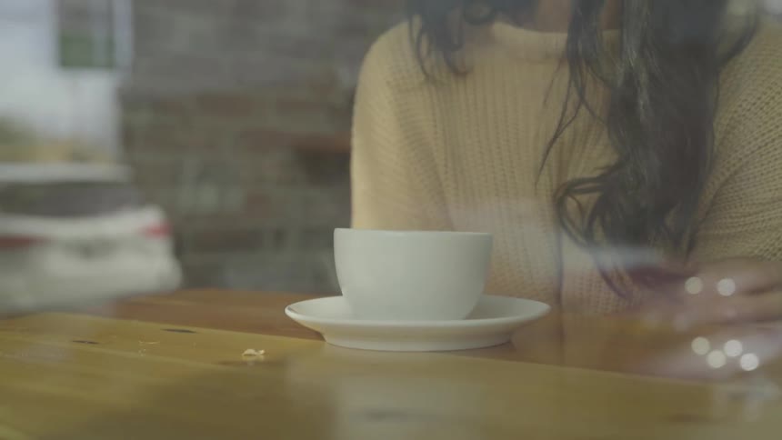 A woman leans in to smell the cup of coffee