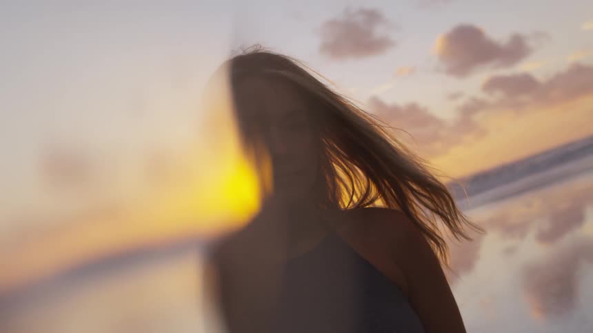 A blonde haired woman on the beach with sunlight shining on her