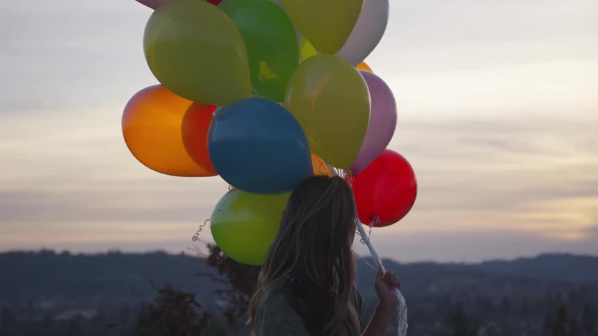 Woman holds many colorful balloons on a pole