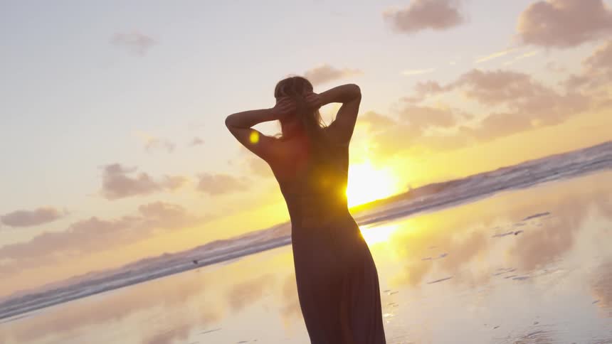 Woman runs hands through hair on beach